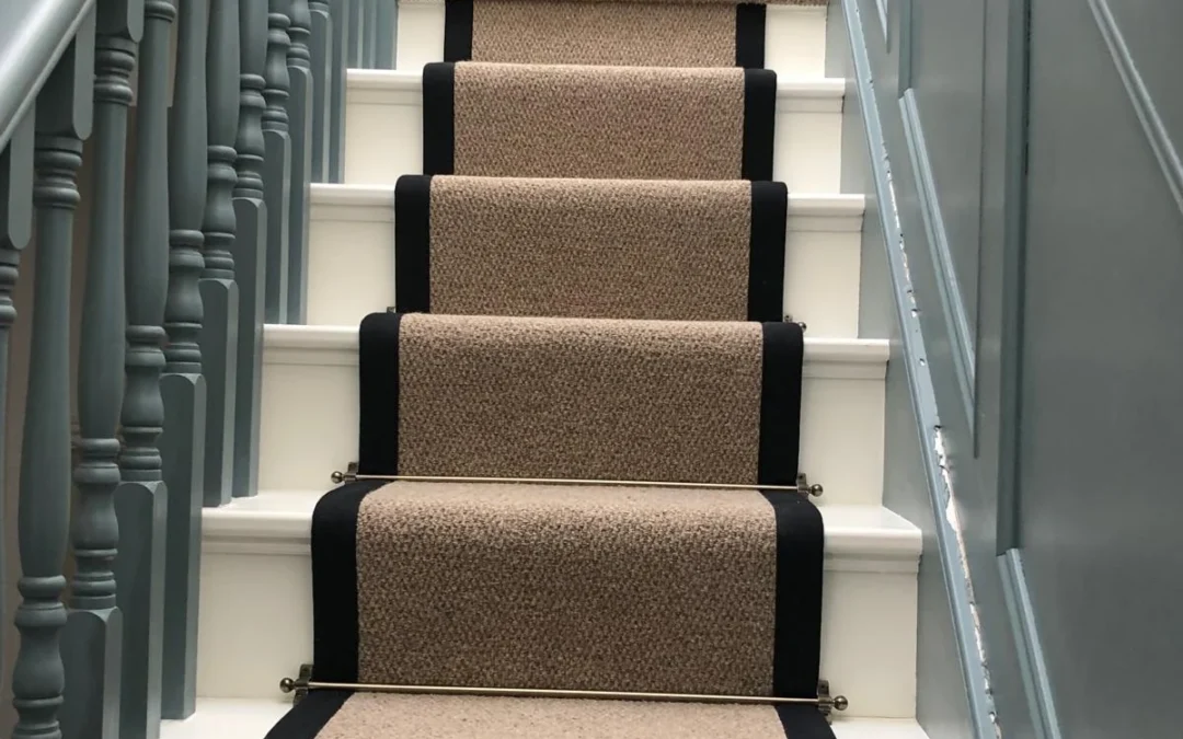 bage-and-black-stair-runner-on-white-stairs-next-to-blue-wall